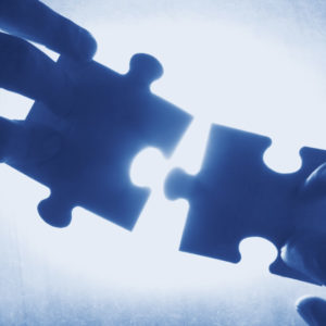 blue contact hands trying to fit two puzzle pieces together